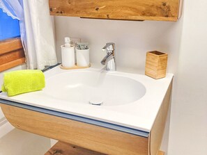 A bathroom with a white sink, wooden cabinet, and a bright green towel. - Scheftenau by Interhome (Wattwil)