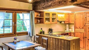 Een landelijke keuken met houten kastjes, een centraal eiland met een spoelbak, en een eetgedeelte met een tafel en stoelen.