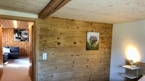 Een kamer met houten lambrisering, een bed, een nachtkastje en een wandlamp.