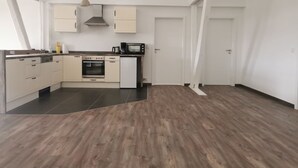 A modern kitchen with white cabinets, a built-in oven, microwave, and dishwasher.