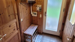 Eine kleine, hölzerne Hütte mit einer Bank, einer Tür mit Frostglas und einem an der Wand montierten Thermostat.