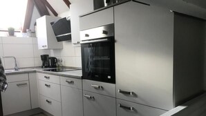 Eine moderne Küche mit grauen Schränken, einem schwarzen Backofen und einer Edelstahl-Dunstabzugshaube.