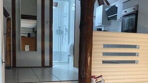 Ein Restaurantinnenraum mit Holztischen und -stühlen, einer Theke und Blick ins Freie.