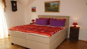 Un dormitorio con una cama, una mesita de noche, una lámpara, un cuadro y un reloj en la pared.