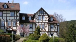 Ein traditionelles Fachwerkhäuschen mit zahlreichen Fenstern und einem gepflegten Garten, durch den eine Treppe zum Eingang führt.