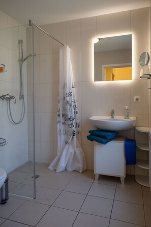A modern bathroom with a glass shower enclosure, a white sink with a mirror above it, and a white toilet. - Kranichnest by Interhome (Bodstedt)