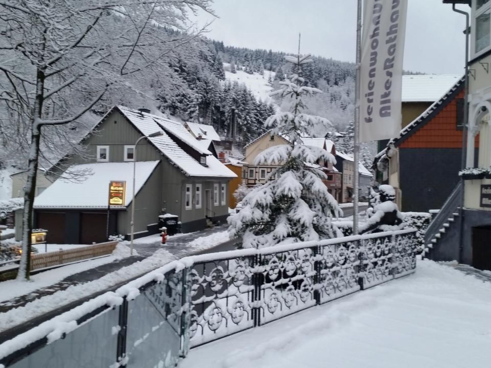 Eine verschneite Straße mit Gebäuden, einem Restaurantschild und einem Berg im Hintergrund.
