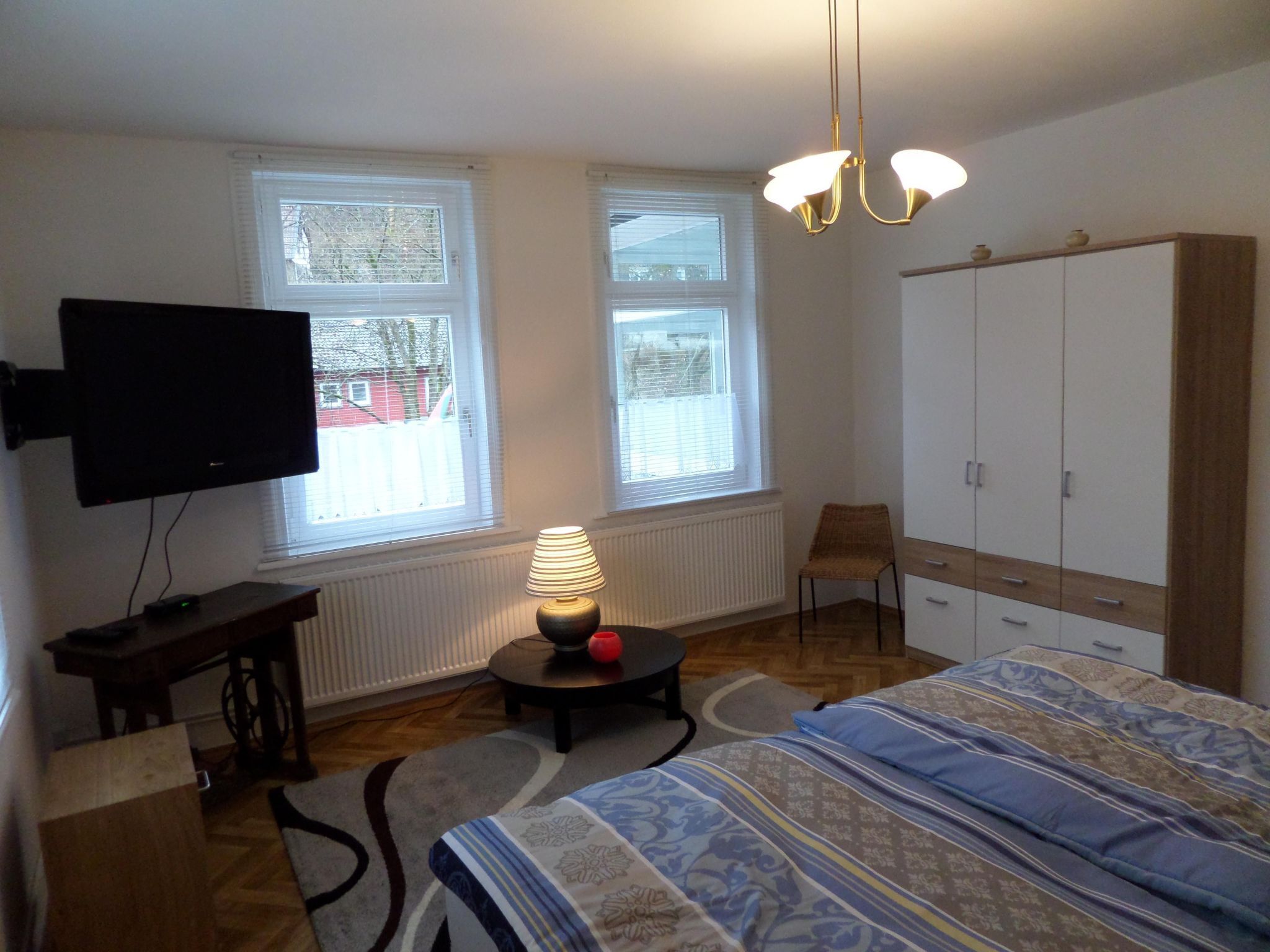 Ein Schlafzimmer mit einem Bett, einem Fernseher, einer Lampe, einem Sessel und einem Kleiderschrank.