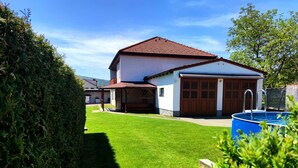 A two-story house with a red-tiled roof, a garage, and a swimming pool.