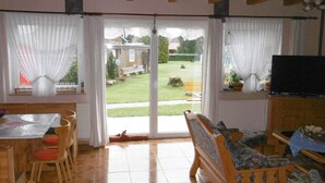 A room with a dining area, a sofa, a television, and a sliding glass door leading to a garden. - für 16 Personen mit Terrasse by Interhome (Sudwalde)