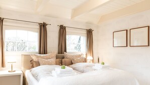 Een slaapkamer met een groot bed, twee nachtkastjes en een raam met gordijnen.
