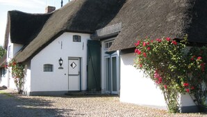 Een klassiek wit gebouw met rieten dak en een groene deur.