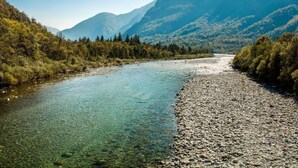 Um rio serpenteando por uma paisagem montanhosa, com águas cristalinas e margens rochosas.