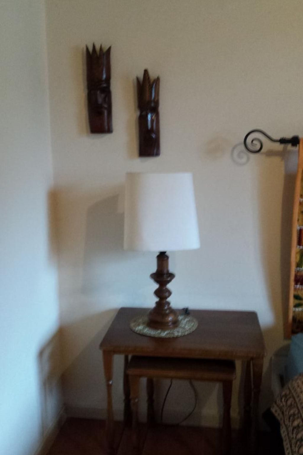 A wooden table with a lamp and a wall-mounted decorative item.