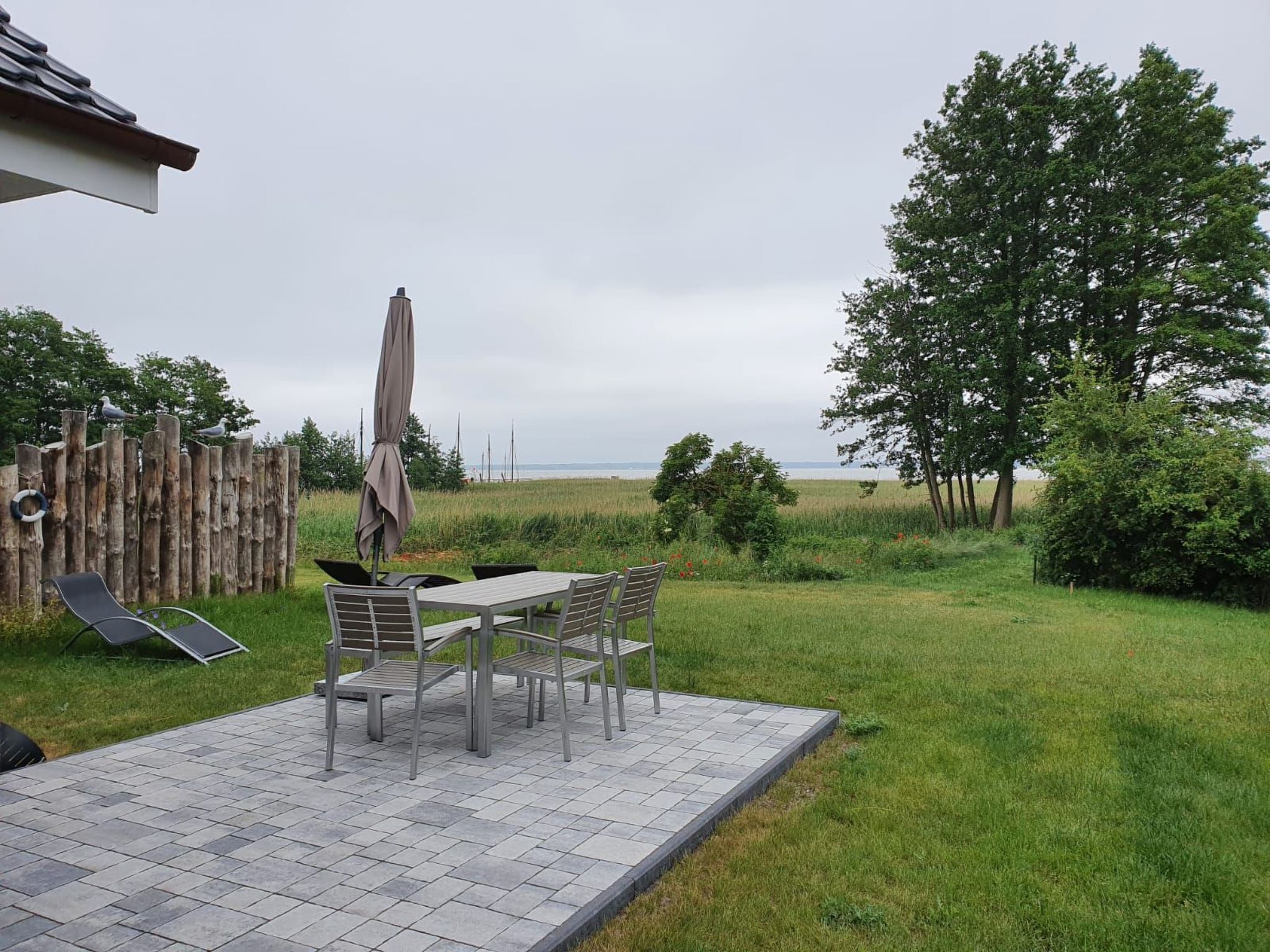 A patio with a table and chairs, a wooden fence, and a view of the sea.