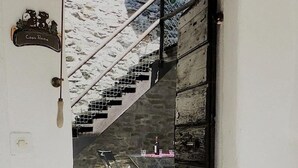 An open door leading to a staircase with a metal railing. A small table with a bottle and glasses is visible on the landing. - Casa Anna by Interhome (Avegno)