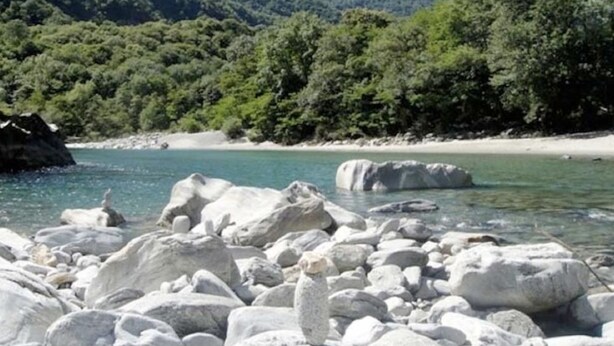 A rocky shoreline with large boulders and a forested mountain backdrop. - Casa Anna by Interhome (Avegno)