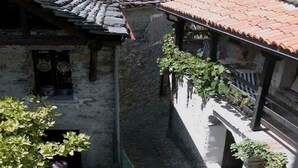 A narrow stone building with a tiled roof, a small entrance, and a balcony with plants. - Casa Anna by Interhome (Avegno)