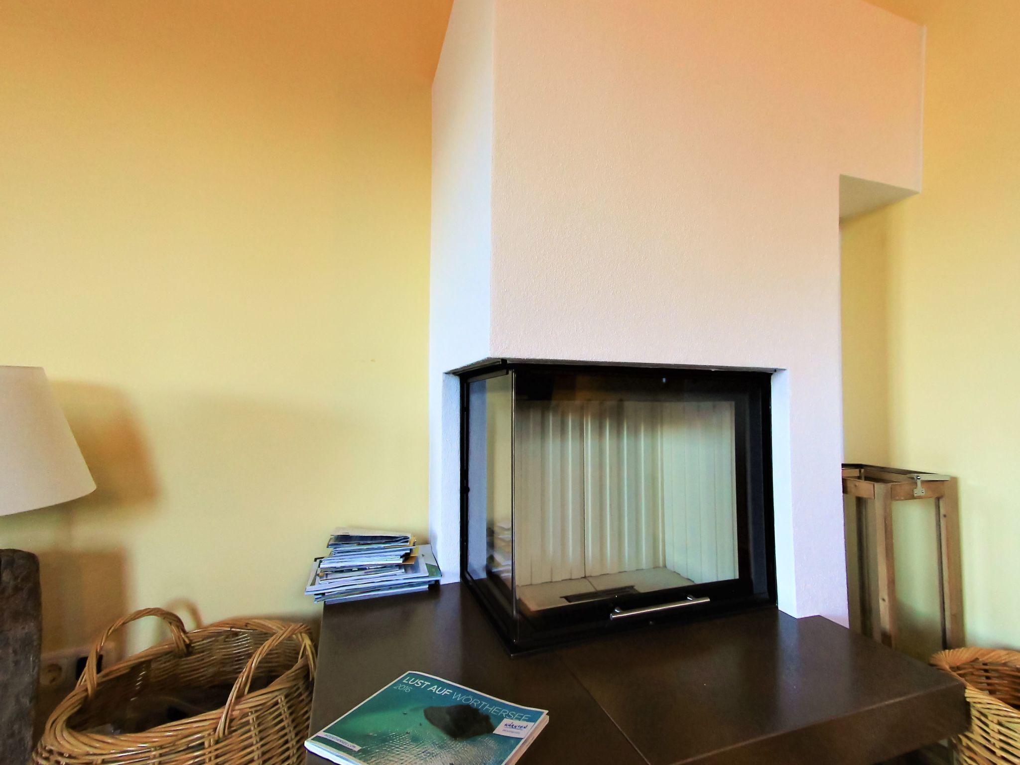 Une pièce avec une cheminée, une table avec des magazines et un panier en osier.