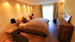 Een slaapkamer met een groot bed, nachtkastjes, een kaptafel, een stoel en een raam met gordijnen.