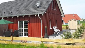 A red barn with a sloped roof, a satellite dish, and a small outdoor seating area with two chairs. - Schwedenhaus Zierow mit Terrasse und Grill by Interhome (Alt Jassewitz)