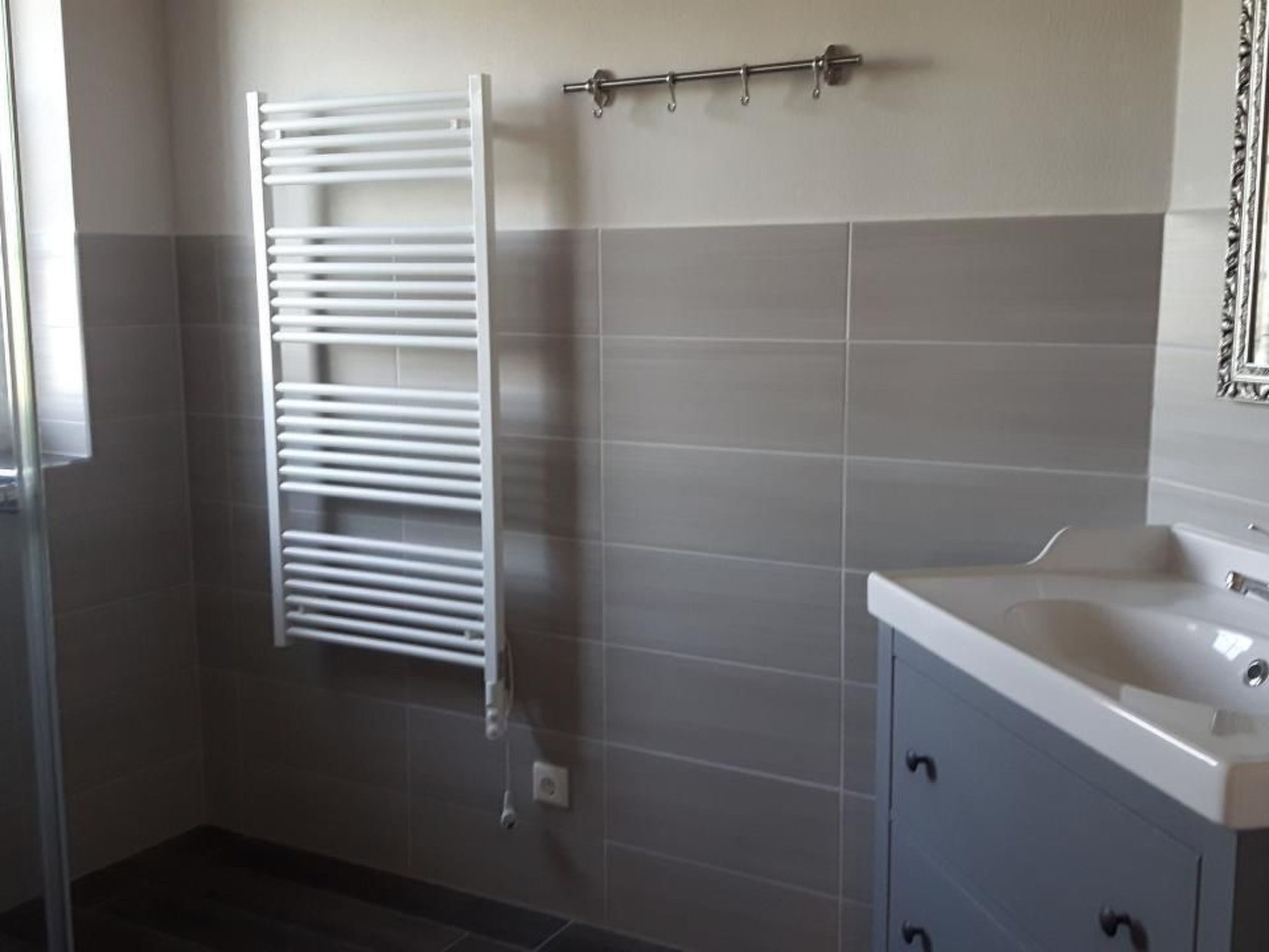A bathroom with a white towel rack, a sink, and a mirror.