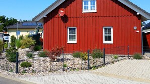 Un bâtiment en bois rouge, doté d’un toit en pente, de deux fenêtres et d’une antenne parabolique.