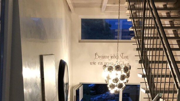 Un escalier moderne avec des rampes en métal et un luminaire suspendu.