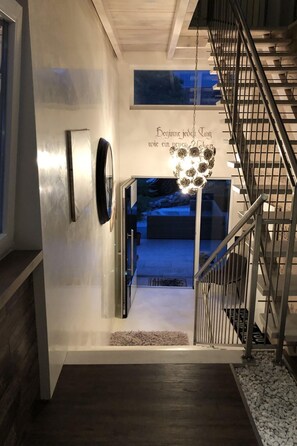 Una escalera moderna con barandillas de metal y un candelabro colgante.