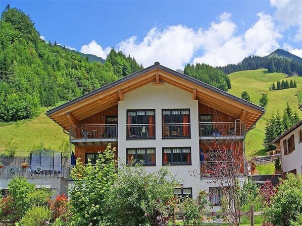 A multi-story building with balconies, surrounded by lush greenery and mountains. - Apartment Höfer by Interhome (Schröcken)