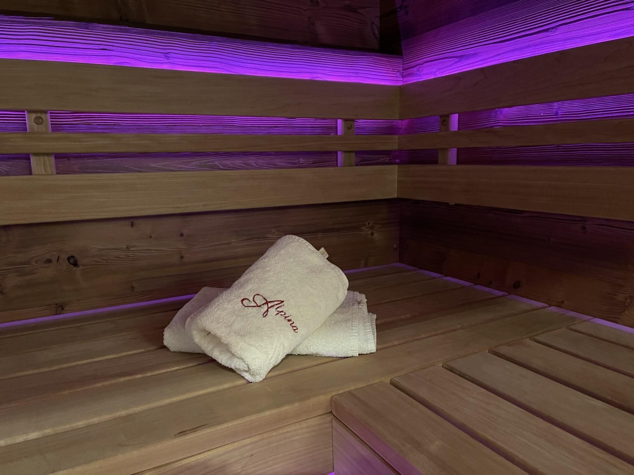 Un banc en bois dans un sauna, sur lequel est posée une serviette portant l’inscription « Ariana ».