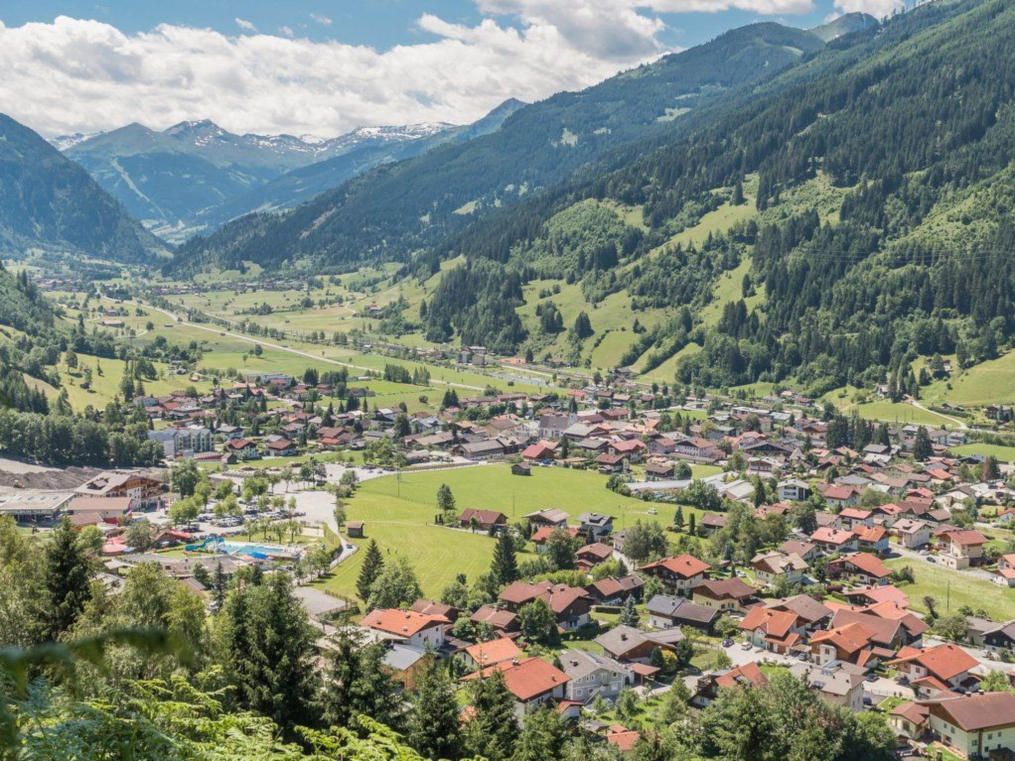 Une ville nichée dans une vallée, où se côtoient des immeubles résidentiels et de vastes espaces verts, le tout étant entouré de montagnes.