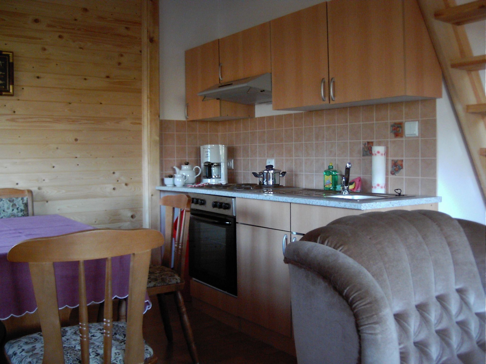 A compact kitchen with wooden cabinets, a coffee maker, a kettle, and a toaster.
