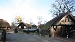 A rustic village setting with traditional thatched-roof buildings, a paved courtyard, and a sign reading "Kobersower Salzhütte." - Wohnung in Koserow mit Garten und Grill und Neben dem Strand by Interhome (Koserow)