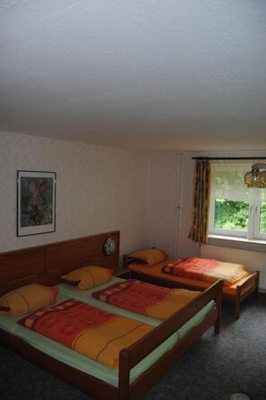 A bedroom with two beds, a wooden headboard, a clock, a window with curtains, and a painting on the wall. - Schule 6 by Interhome (Eckernförde)
