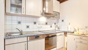 Een keuken met witte kastjes, een roestvrijstalen spoelbak, een fornuis en een magnetron.