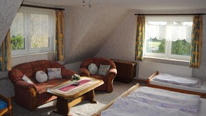 Um quarto de sótão acolhedor com duas sofás, uma mesa de madeira e uma cama.