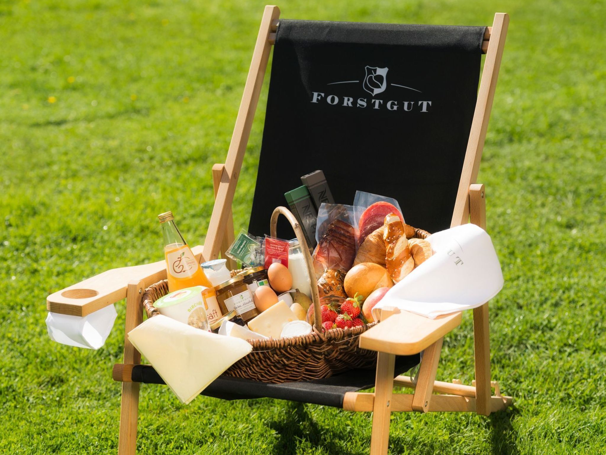 A wooden chair with a black cover labeled "FORSTGUT" on a grassy field.