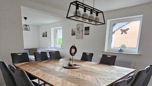 Ett konferensrum med ett stort bord i trä, svarta stolar och en modern hänglampa.