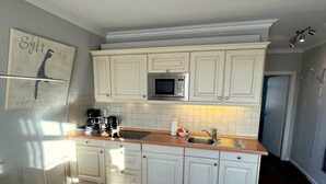 A kitchen with white cabinets, a microwave, a coffee maker, and a sink. - Wohnung mit Sonnenbalkon und Strandnähe by Interhome (Wenningstedt-Braderup)