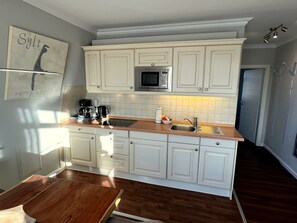 A kitchen with white cabinets, a microwave, a coffee maker, and a sink. - Wohnung mit Sonnenbalkon und Strandnähe by Interhome (Wenningstedt-Braderup)