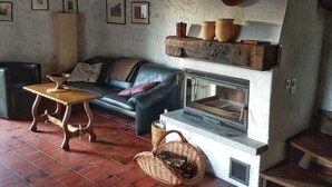 Un salon rustique avec un mur en pierre, une cheminée, un canapé et une table en bois.