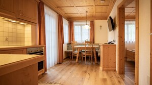 Une cuisine chaleureuse avec des meubles en bois, une table à manger et un téléviseur fixé au mur.
