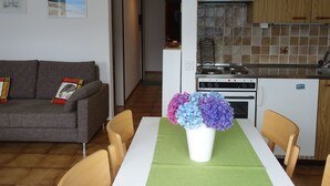 Una cucina moderna con piano cottura bianco, mobili in legno e una lampada colorata a sospensione.