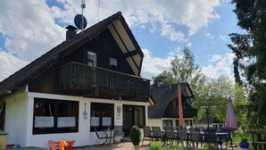 A two-story building with a balcony, outdoor seating area, and a children's play area. - Vacation home Elster by Interhome (Frielendorf)