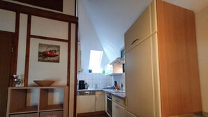 Kompakti keittiö, jossa on puinen pöytä, astianpesukone ja kaapit.