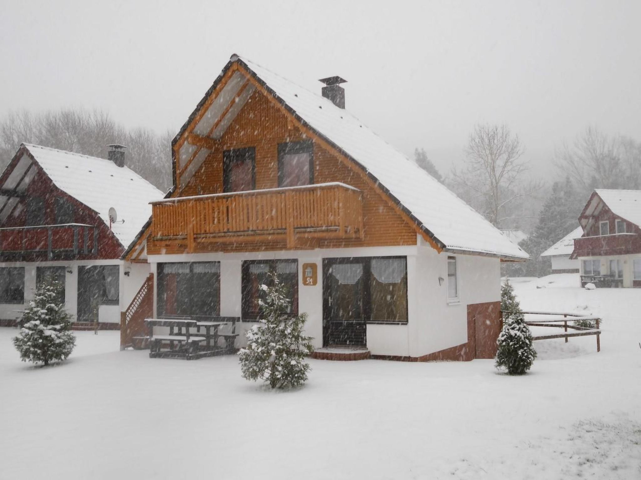 A wooden chalet with a sloped roof, a balcony, and a front entrance.