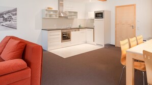 Una cocina moderna con armarios blancos, electrodomésticos de acero inoxidable y una viga de madera en el techo.