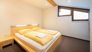 Un dormitorio con cama, mesita de noche, ventana y viga de techo de madera.