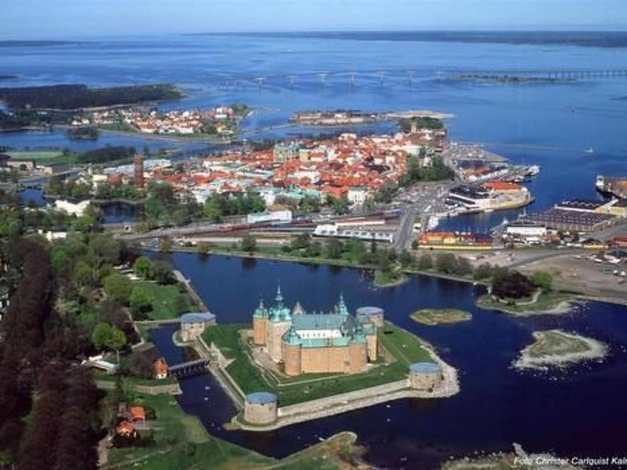 Vue aérienne d’une ville historique, avec un château imposant et une rivière.